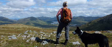 Hill walker and dog enjoying the view in the Scottish Highlands