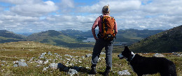 Walker and dog looking out across the mountains